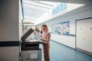 Teacher is printing off work sheets for her next lesson using the printer in the school hall.