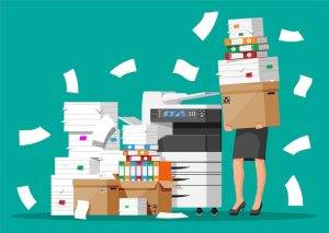 Stressed businesswoman carries a heavy box of printer paper to the printer.