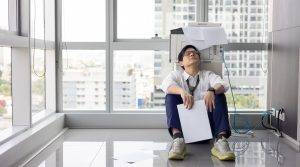 Office worker is sitting beside broken copier at the office.